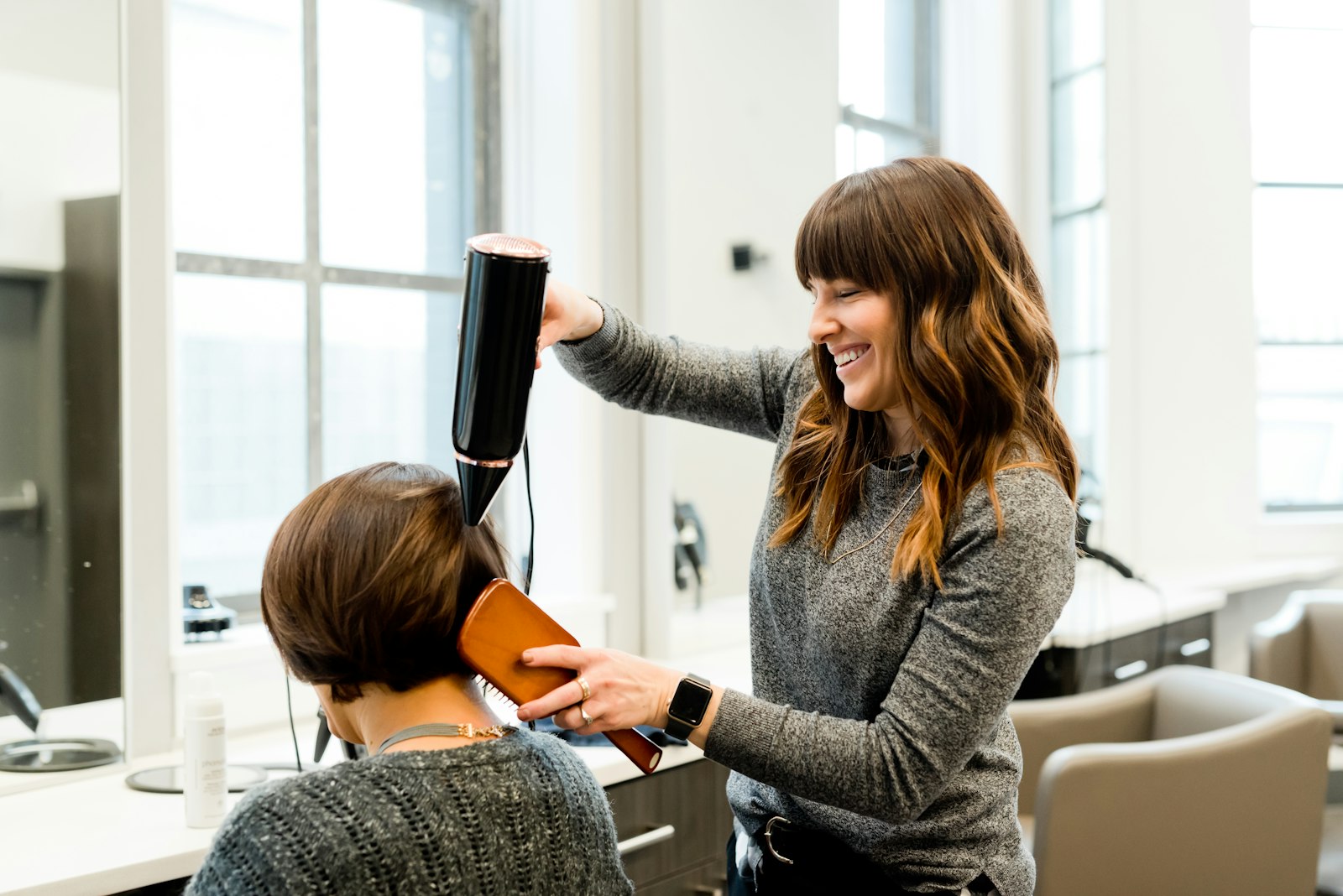 Penata rambut mengeringkan rambut dengan hair dryer